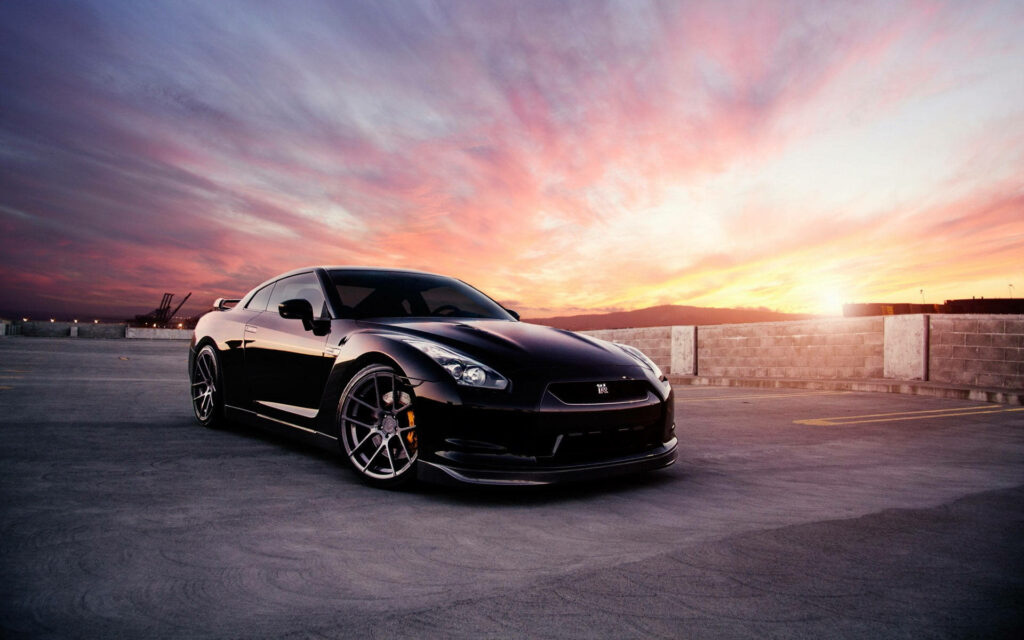Sleek black car with glossy finish against dramatic vibrant sunset sky high definition wallpaper