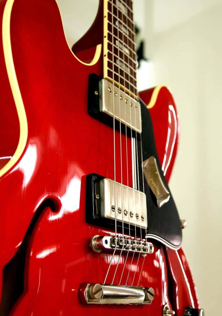 Close-up of glossy cherry red semi-hollow electric guitar with chrome pickups and cream binding Wallpaper