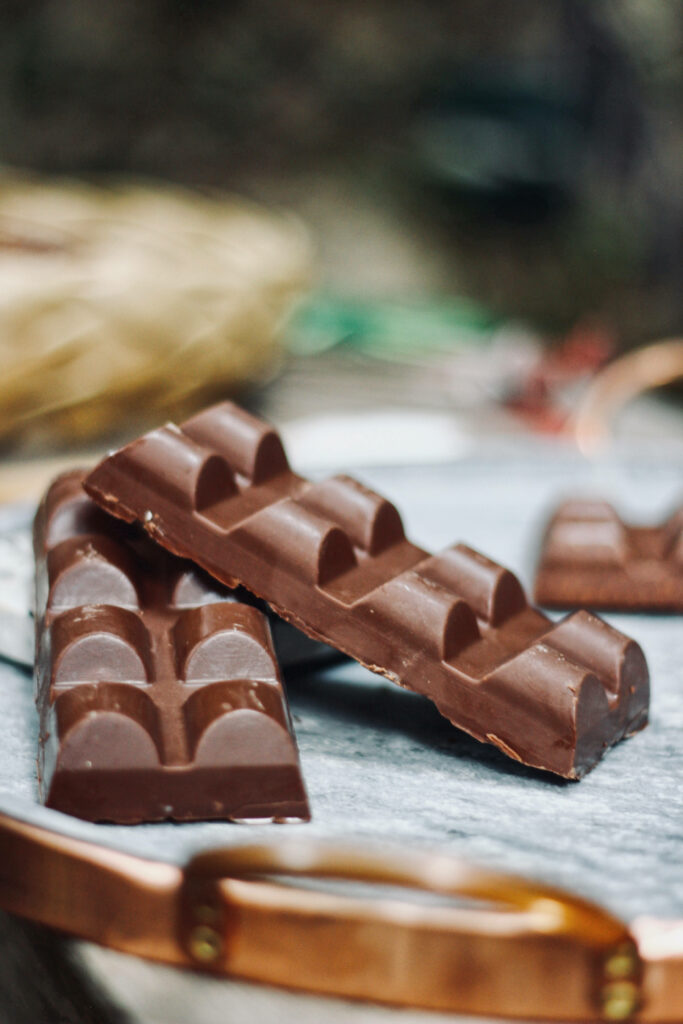 Close-up of glossy rich chocolate bars on rustic metal tray with soft warm background lighting Wallpaper