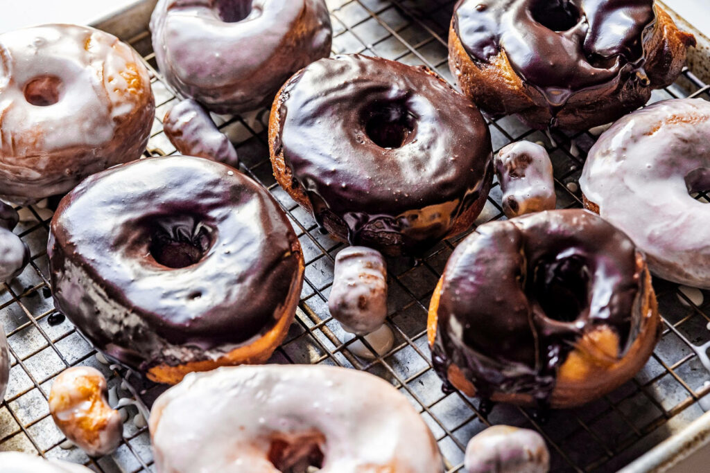 Colorful donuts with glossy chocolate and vanilla glaze on cooling rack dessert wallpaper