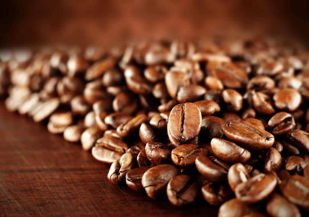 Close up of glossy coffee beans with rich texture on rustic wooden surface wallpaper background