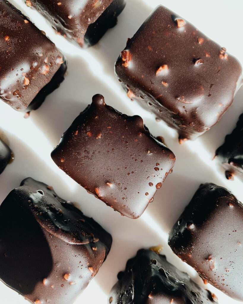 Top view of glossy dark chocolate cubes arranged on white background with rich texture details Wallpaper