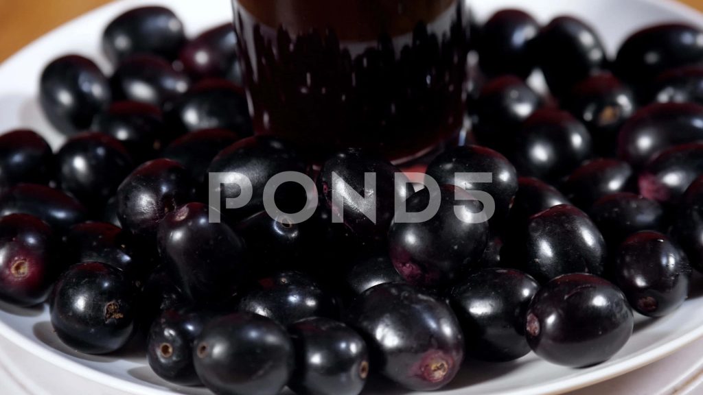 Glossy deep dark purple Java plums on white plate with glass of juice fresh nature wallpaper