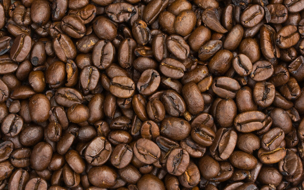 Close-up of glossy dark roasted coffee beans wallpaper evoking warm fresh coffee aroma background