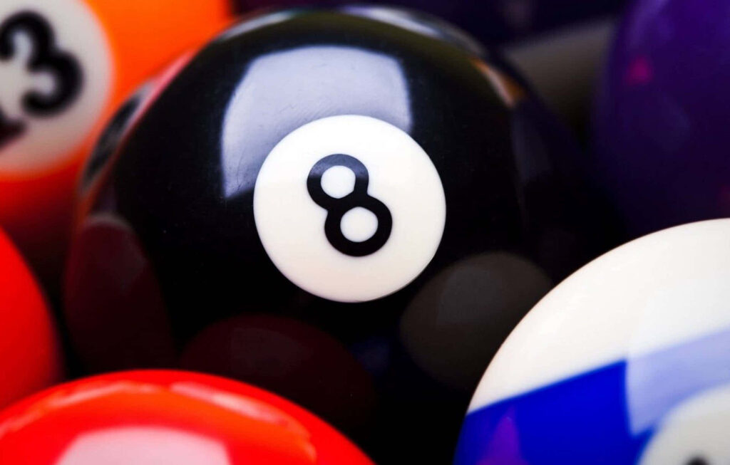Glossy black eight ball close-up surrounded by colorful pool balls vibrant billiards wallpaper