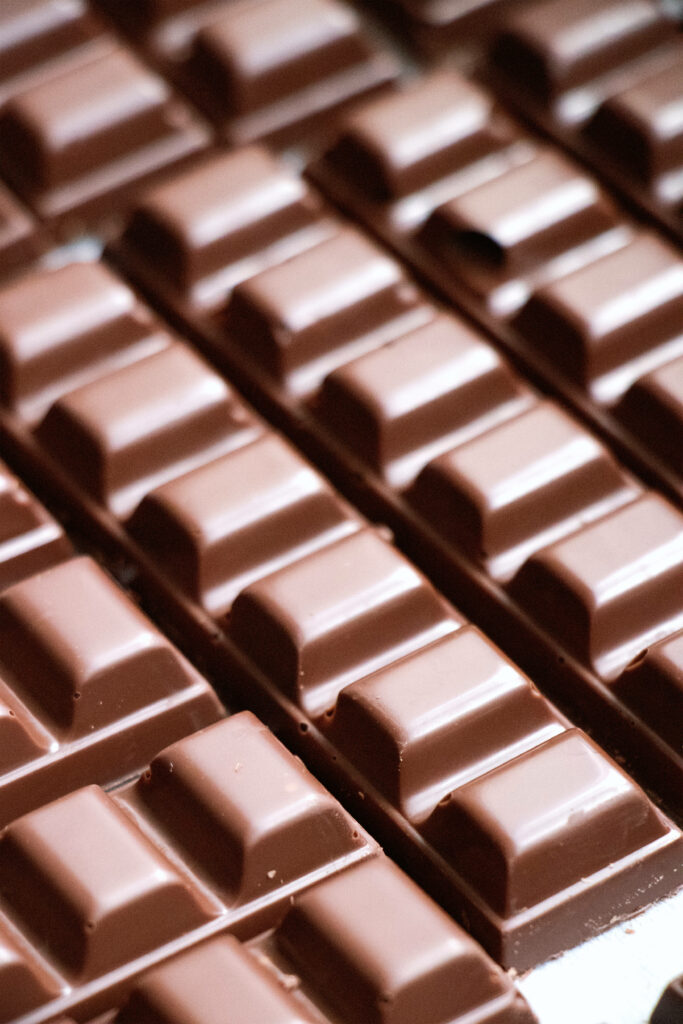 Close-up of smooth glossy milk chocolate bars in neat rows with rich brown tones wallpaper background