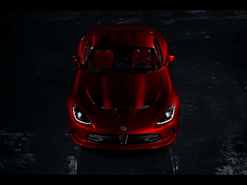 Glossy red Dodge Viper top view highlighting sleek curves aggressive design on dark background Wallpaper