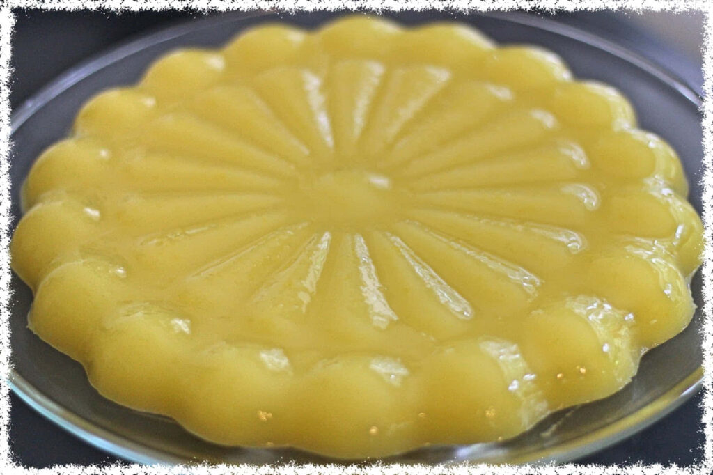 Glossy yellow Blancmange dessert with decorative mold pattern appealing wallpaper background