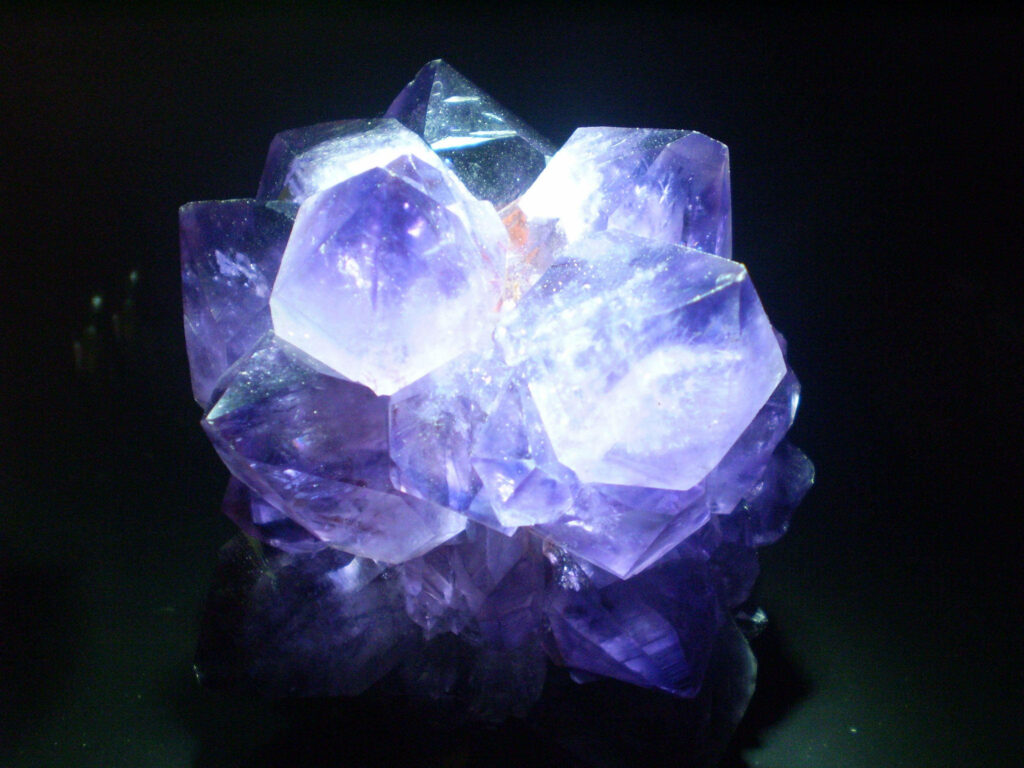 Close-up of glowing amethyst crystal cluster with deep violet hues and intricate facets wallpaper background