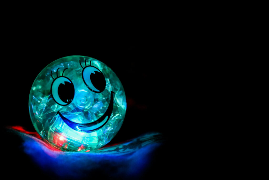 Glowing with Happiness: A Vibrant Blue Emoji Ball Shining in the Dark Wallpaper