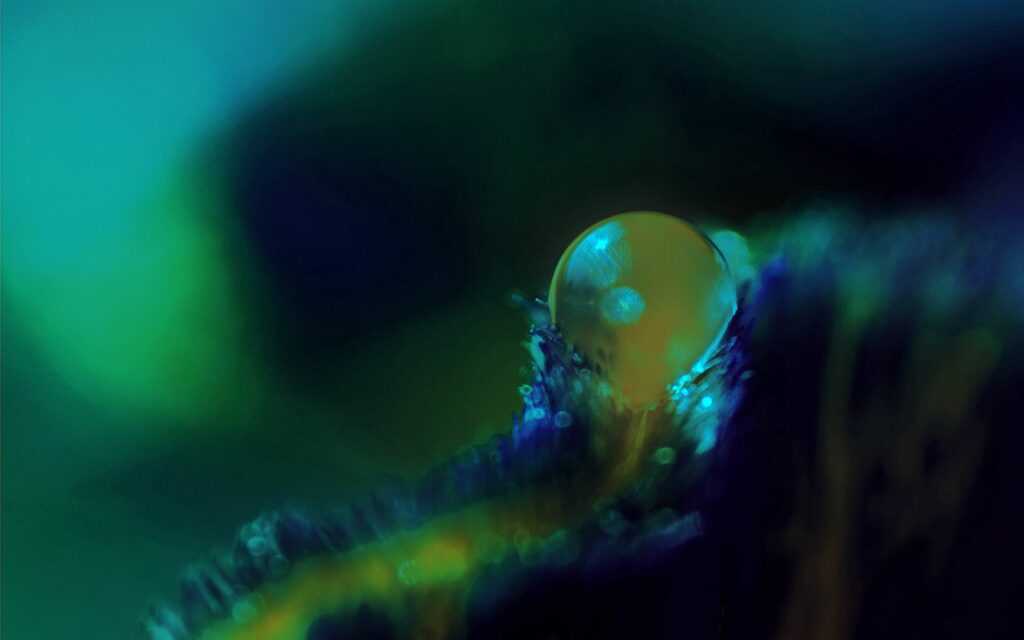 Glowing Drop on Textured Surface: Mysterious Green & Blue Wallpaper