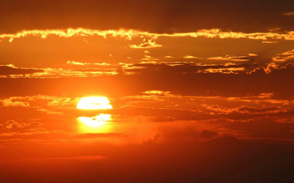 Glowing orange and gold sunset with dramatic clouds creating a tranquil romantic evening sky Wallpaper