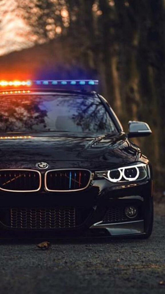 Law Enforcement on the Move: Sleek Black BMW Police Car with Flashing Lights Wallpaper