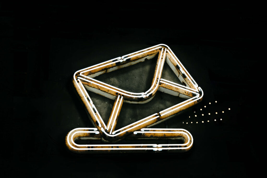 Glowing neon email icon with white and yellow outlines on dark background digital communication wallpaper