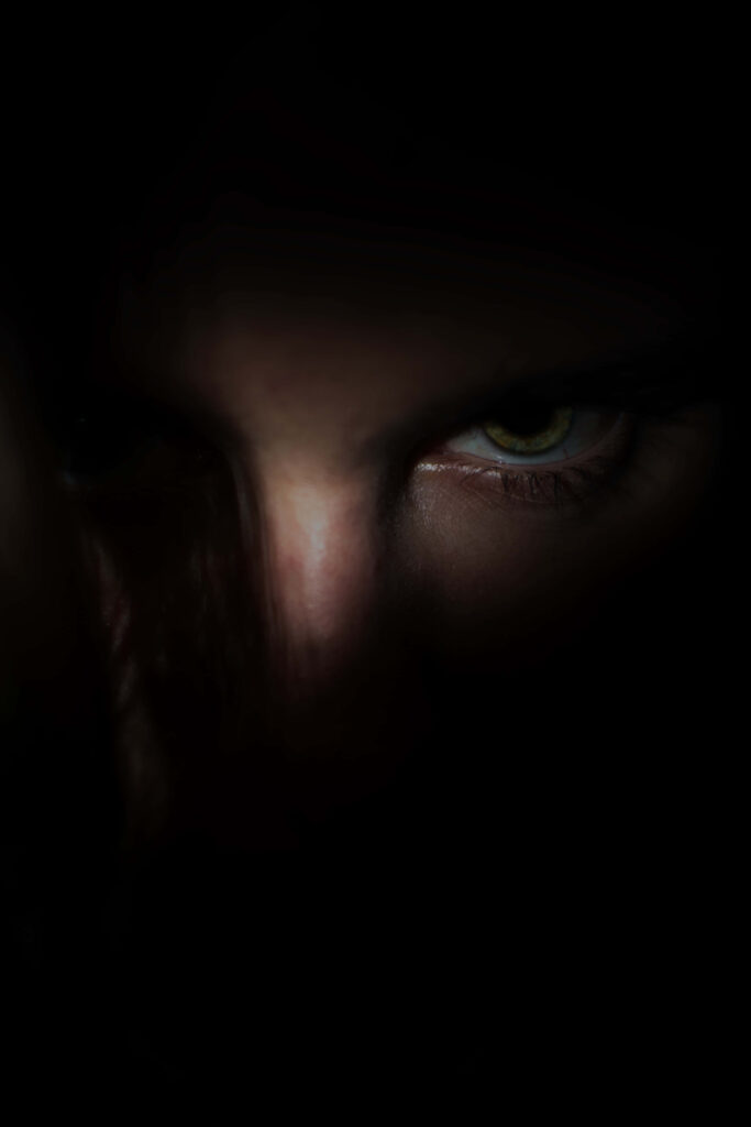 Glowing sharp eye piercing through shadows dark intense mysterious wallpaper background