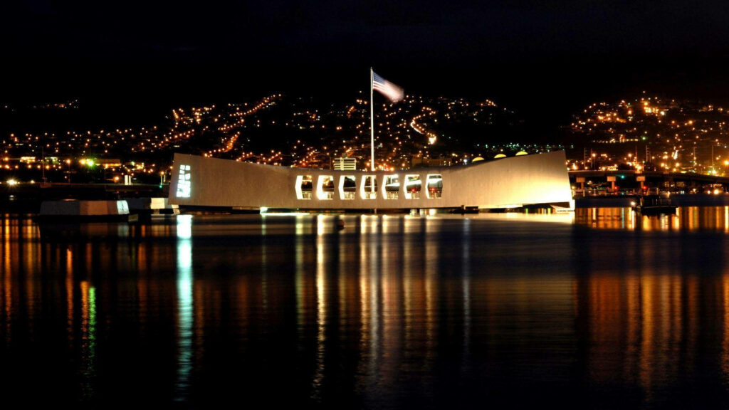 Glowing USS Arizona Memorial Pearl Harbor night reflection calm waters city lights USA Memorial Day Wallpaper