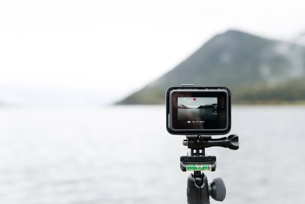 GoPro camera on tripod capturing 4K wide-angle misty mountains and water serene landscape Wallpaper