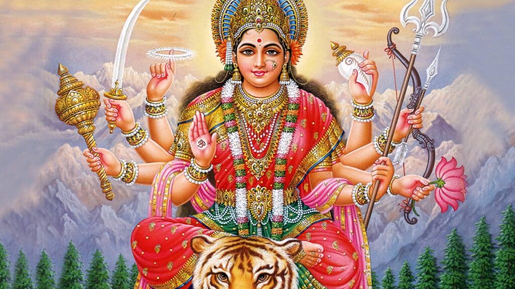 Hindu Goddess Durga in red gold attire on tiger with weapons mountain backdrop spiritual wallpaper