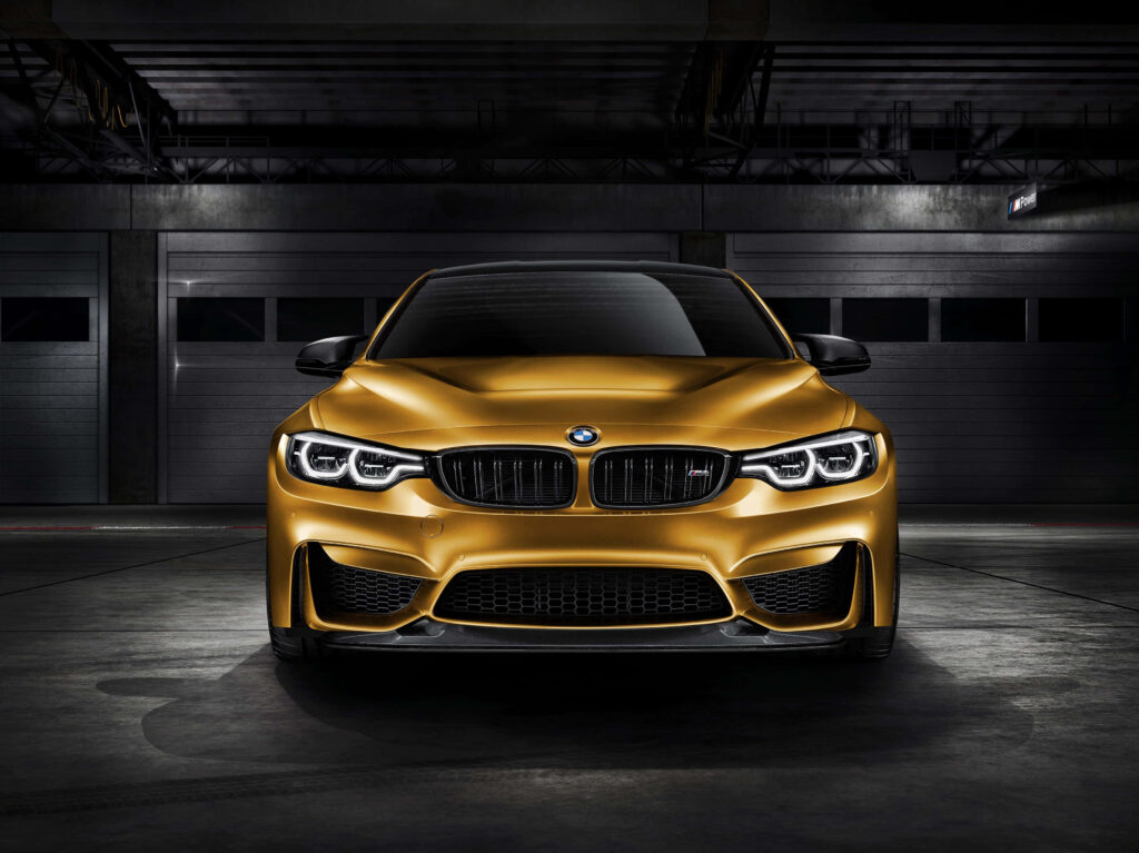 Gold BMW M4 in dark garage showcasing bold design and luxurious sleek finish wallpaper background
