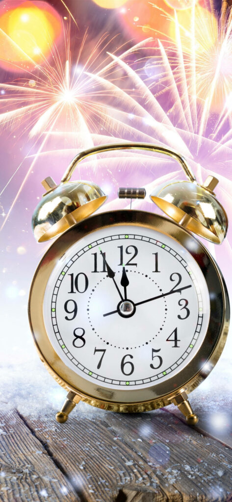 Golden alarm clock near midnight on frosty wood with fireworks vibrant New Year countdown background Wallpaper