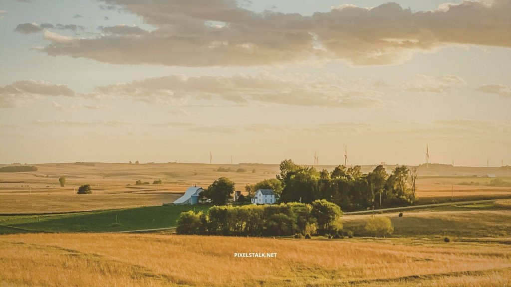 Golden fall countryside with cozy farmstead rolling fields and wind turbines at sunset Wallpaper