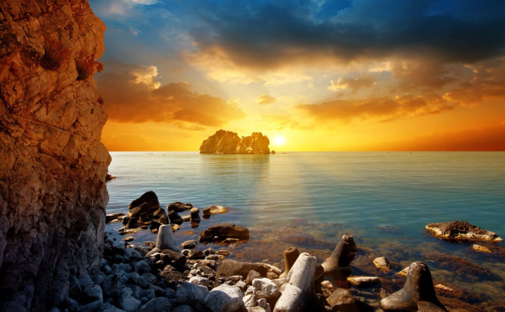 Golden Beach Sunset Over Tranquil Waters and Rocky Shores Wallpaper
