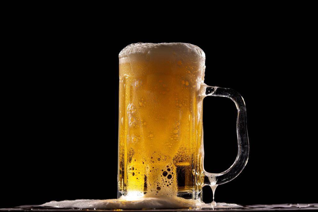 High-resolution beer wallpaper showing a glass mug with golden brew and frothy foam on black background