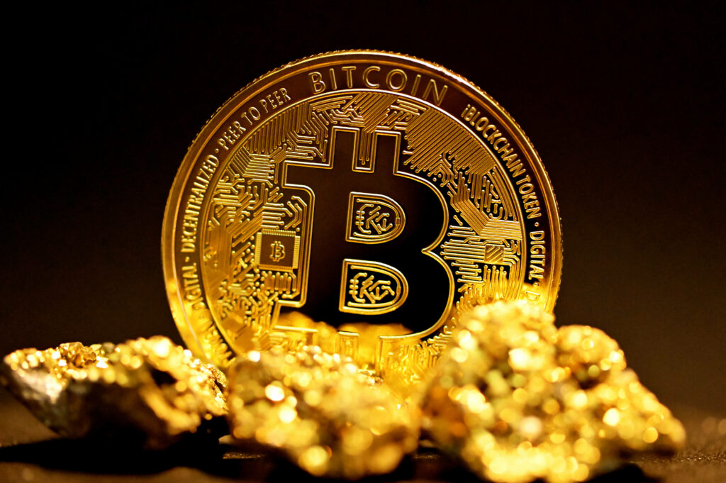 Golden Bitcoin coin standing upright among gold nuggets symbolizing cryptocurrency value wallpaper