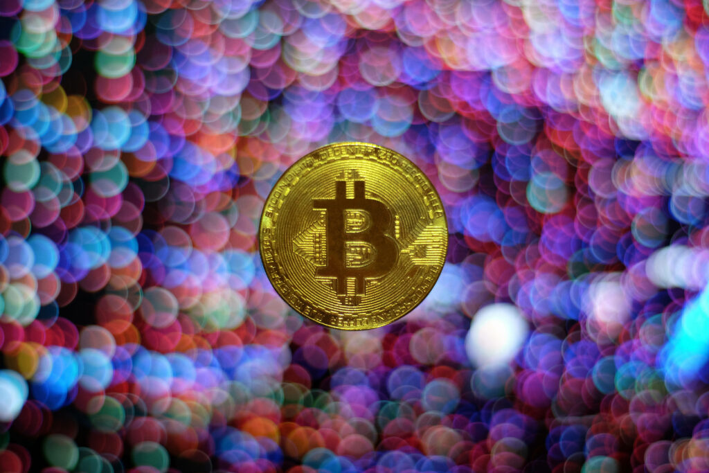 Golden Bitcoin coin with vibrant colorful blurred lights symbolizing crypto revolution background Wallpaper