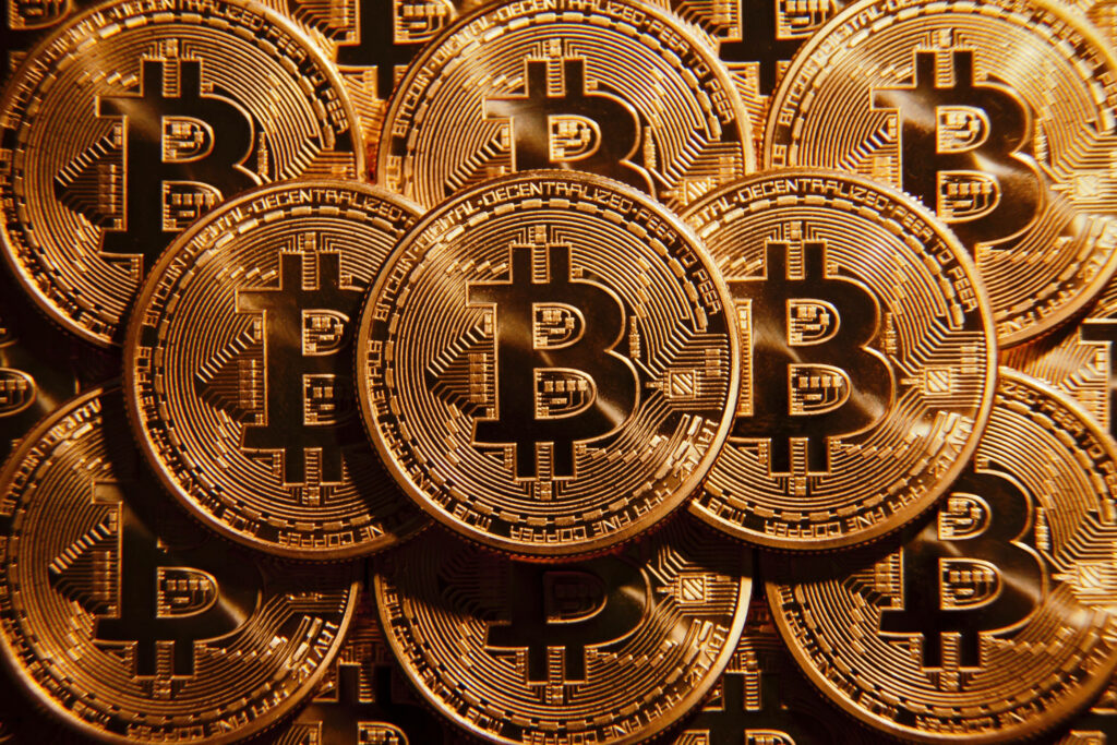Close up of multiple golden Bitcoin coins representing cryptocurrency disruption in finance Wallpaper