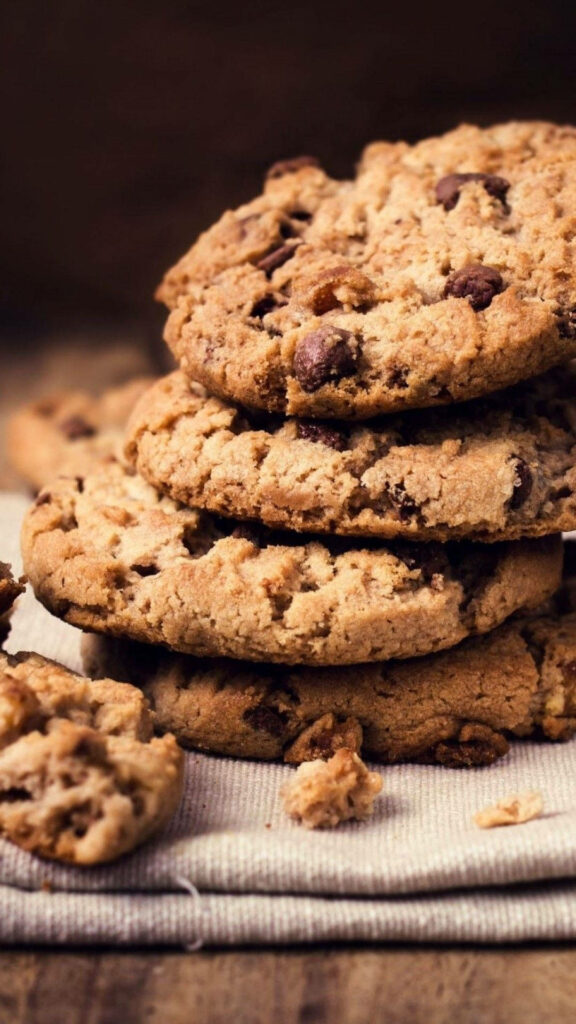 Stack of golden brown chocolate chip cookies on striped cloth with melty chocolate chips texture Wallpaper