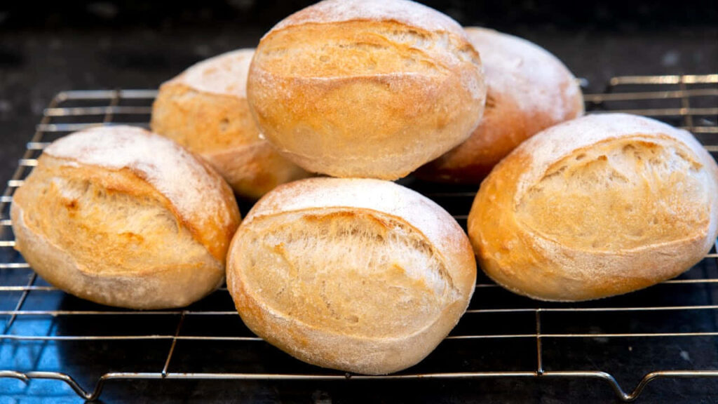 Golden Brown Crusty Bread Rolls on Cooling Rack - Wallpaper Background