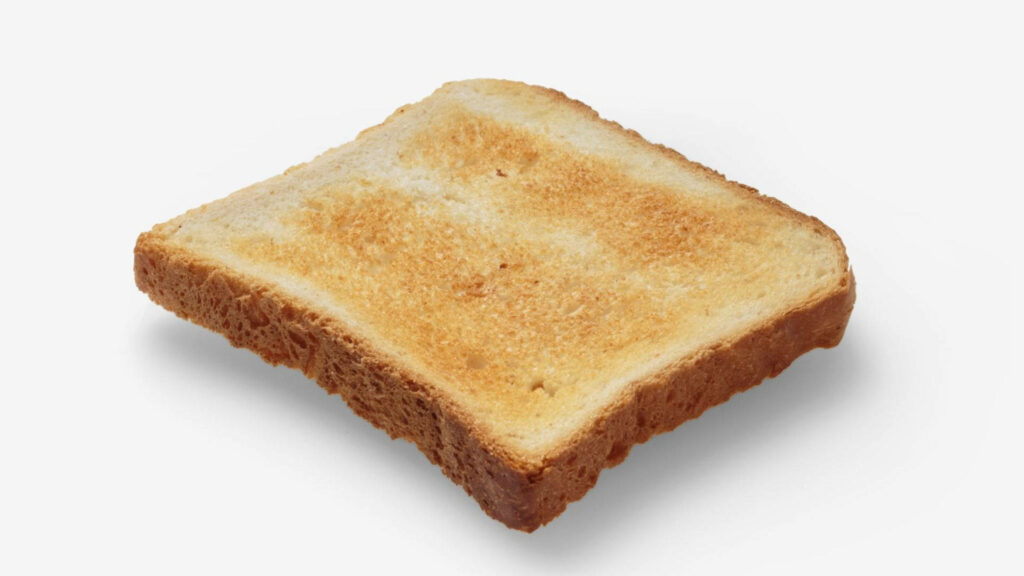 Close-up of golden toasted bread slice with crisp texture and crumbs on white background wallpaper