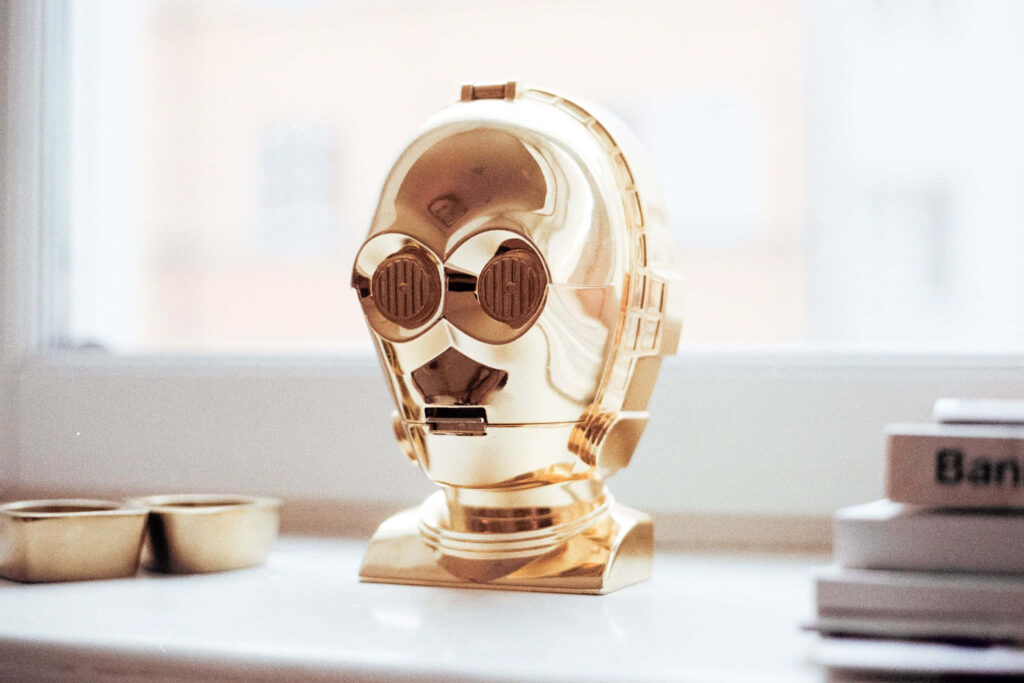 Detailed golden C-3PO bust on bright windowsill with natural light and minimal background wallpaper