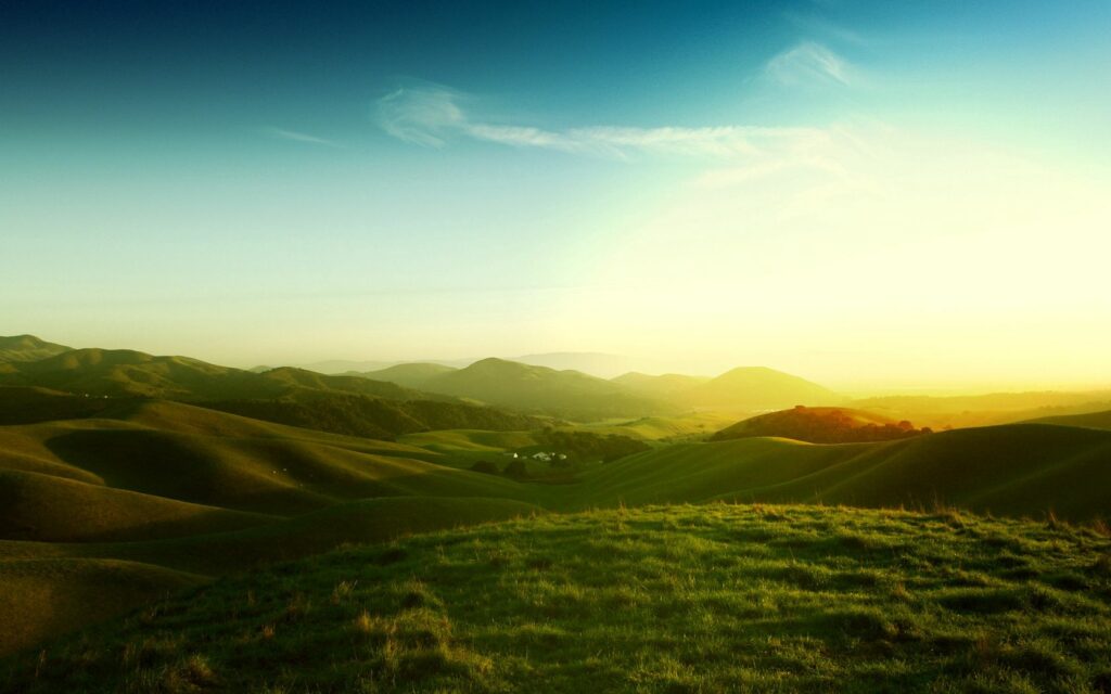 Sunset over California rolling meadows and hills with golden light and clear blue sky wallpaper