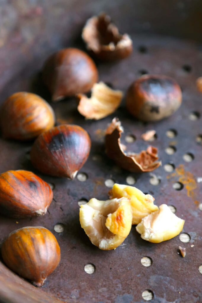 Golden chestnuts scattered on rustic perforated metal evoke warm autumn cozy seasonal textures Wallpaper