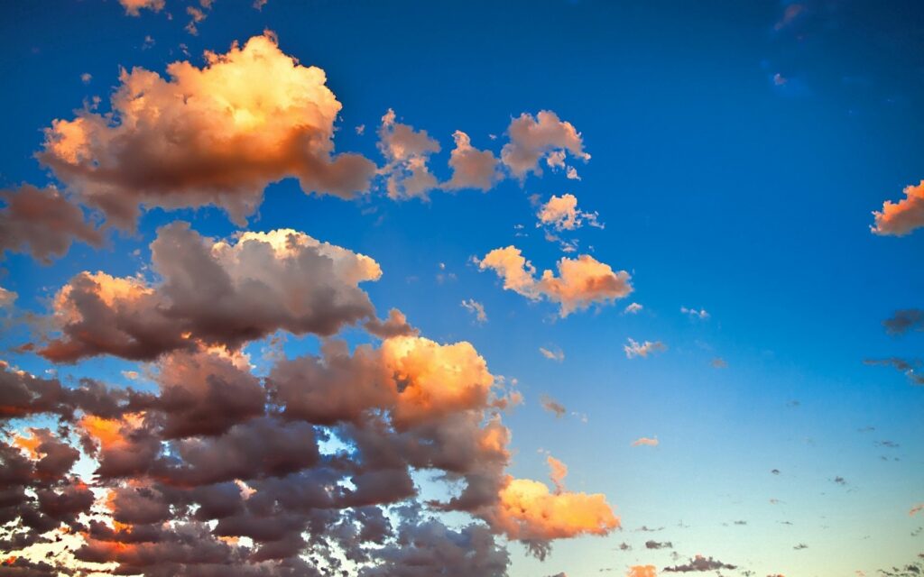 Vibrant golden clouds against clear blue sky wallpaper creating serene and airy atmosphere