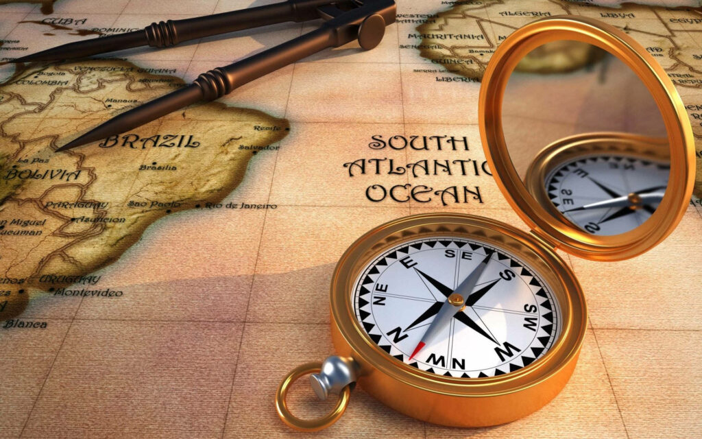 Golden compass on antique map wallpaper with vintage navigation theme and warm textured tones