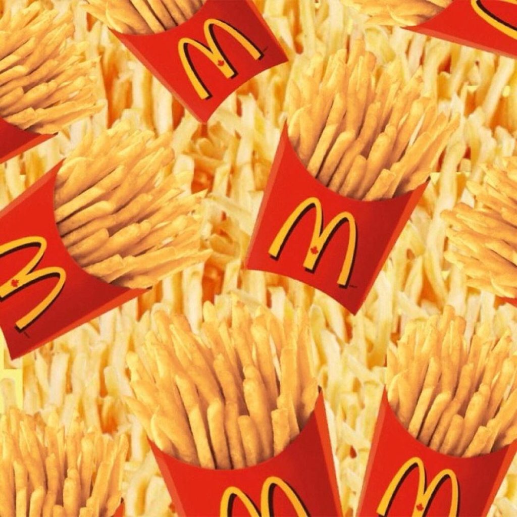Vibrant wallpaper of McDonald’s crispy golden French fries in red cartons repeating pattern