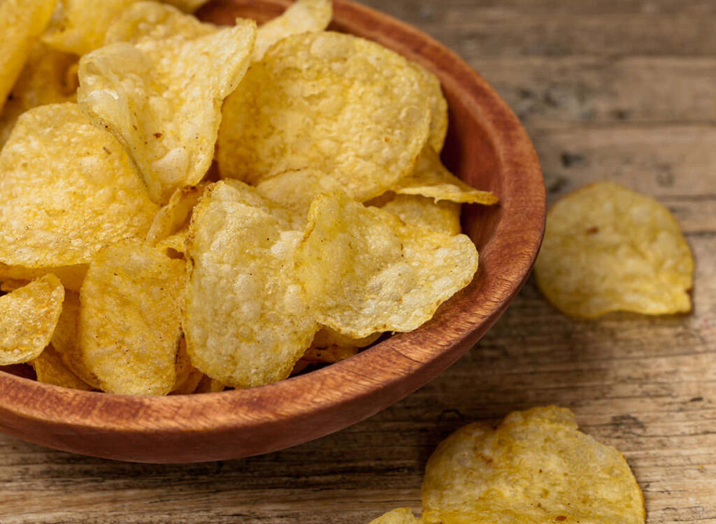 Crispy Golden Potato Chips in Rustic Bowl - Tempting Snack Wallpaper