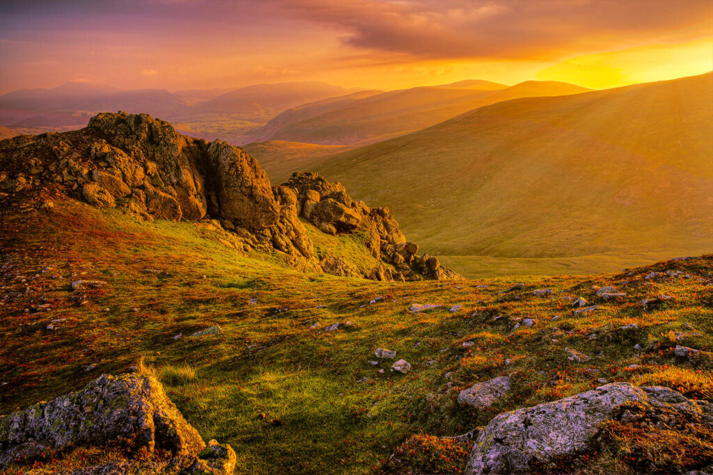 Breathtaking mountain landscape at dawn with rugged rocks lush grass and golden sunlight wallpaper