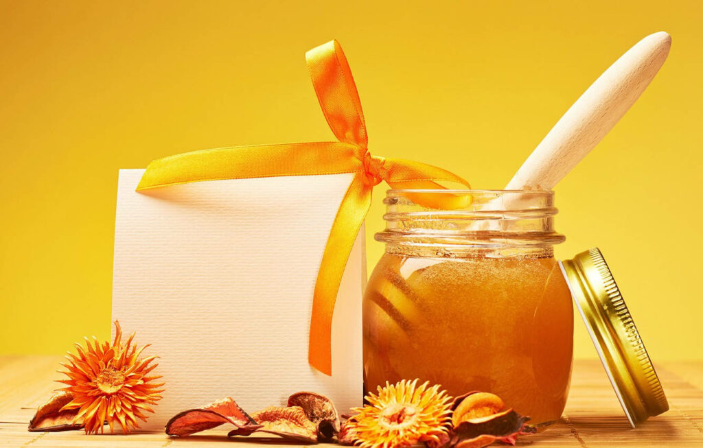 Golden Honey Jar Surrounded by Sweet Potpourri on Vibrant Yellow Wallpaper