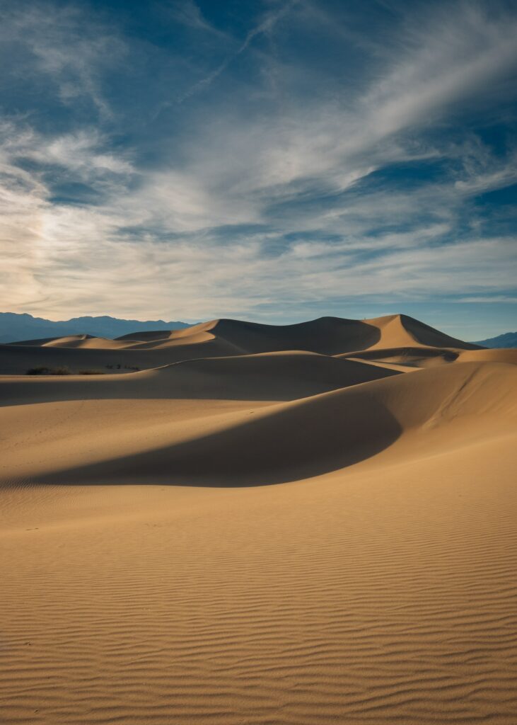 Desert landscape wallpaper with golden sand dunes blue sky and wispy clouds serene scene