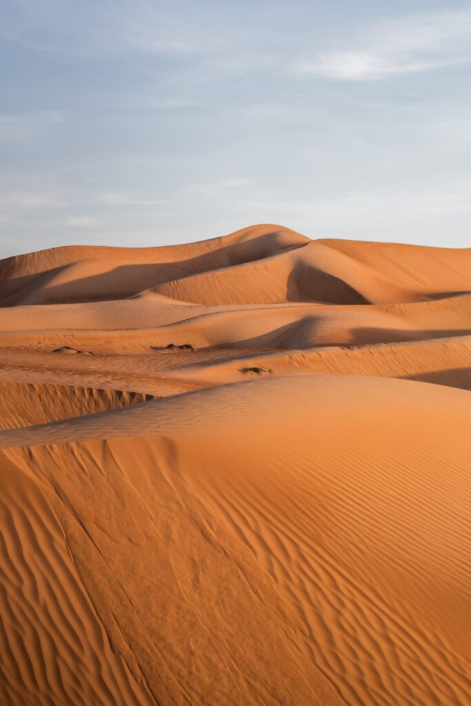 Expansive desert landscape with smooth sandy hills golden tones clear sky nature wallpaper