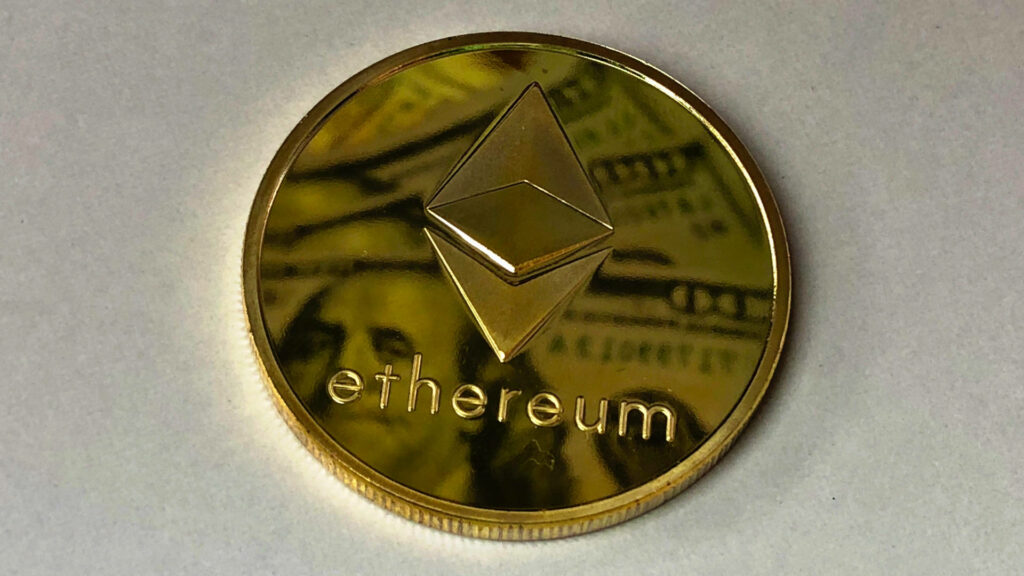 Golden Ethereum coin with metallic sheen on subtle financial themed digital wallpaper background
