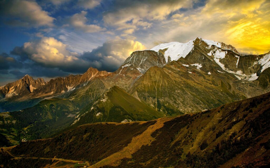 Dramatic mountain landscape with snow-capped peaks and golden evening sky vibrant ridges Wallpaper