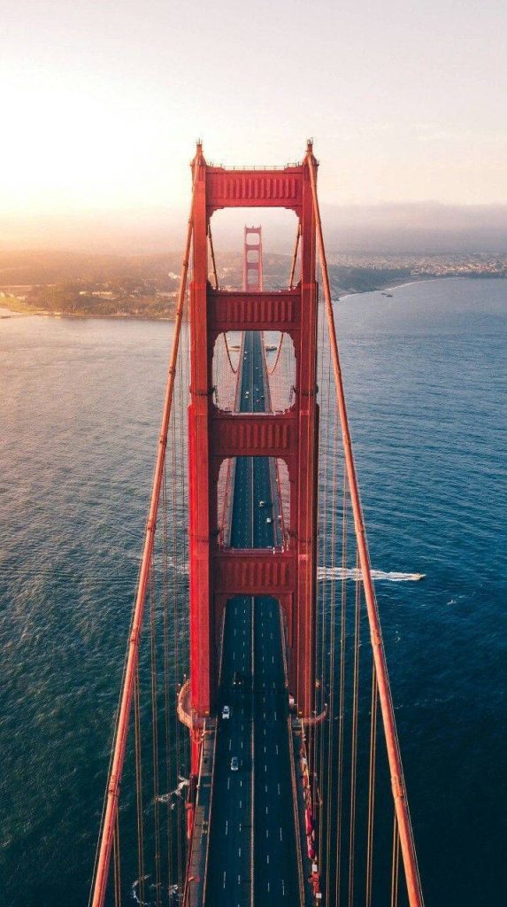 Aerial view of Golden Gate Bridge orange towers over deep blue San Francisco Bay at sunset Wallpaper