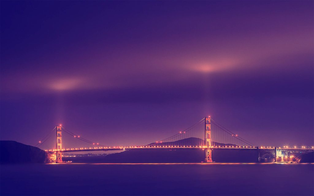 Golden Gate Bridge at night with amber lights purple sky and glowing beams desktop wallpaper