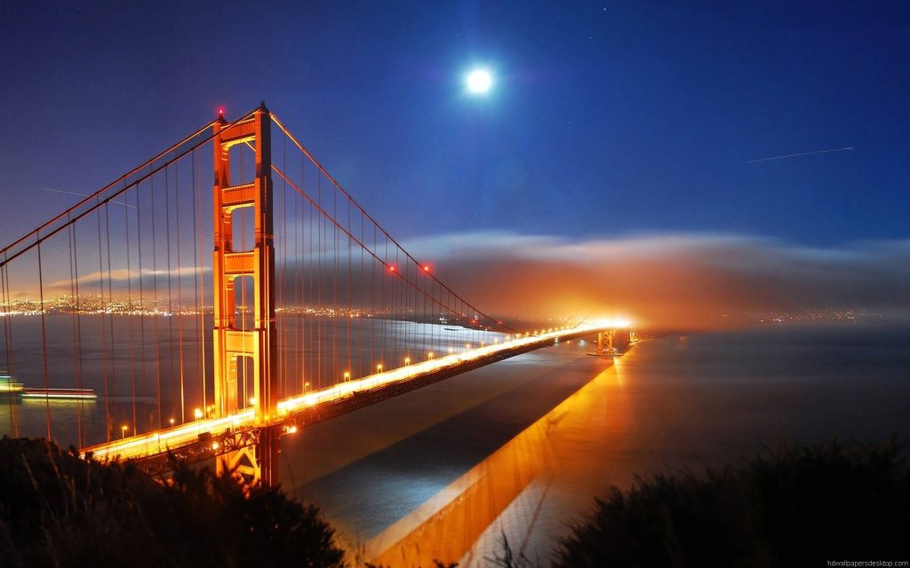 Golden Gate Bridge glowing amber at night with fog over bay perfect desktop wallpaper background