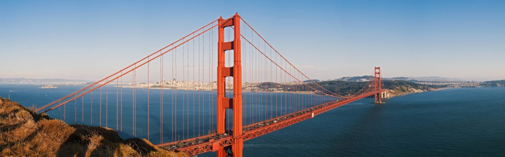 Panoramic Golden Gate Bridge San Francisco International Orange steel against blue bay skyline Wallpaper